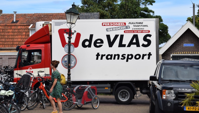 Kleiner Lieferwagen von DeVLAS Transport auf Terschelling mit Stelleninserat — Marke und Mitarbeitende als Einheit.