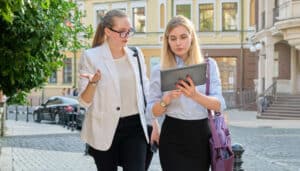 KI im KMU: Zwei Frauen stehen im Freien und besprechen gemeinsam Inhalte auf einem iPad. Das Bild steht für den Austausch von Informationen und die Zusammenarbeit mit Stakeholdern.